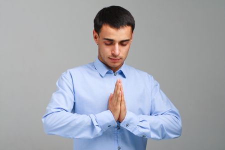 Namaste. Praying business man on a gray background.の写真素材