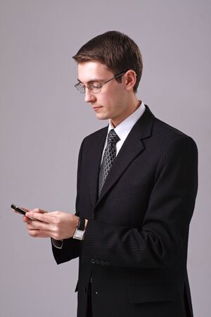 Young businessman with mobile phone, isolated on gray backgroundの写真素材