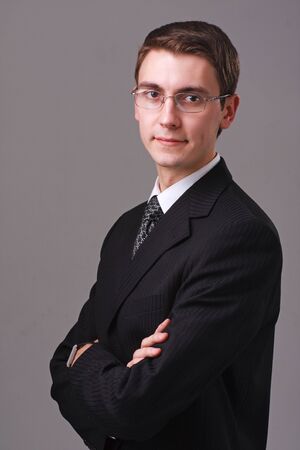 Portrait of young businessman in glasses on a gray backgroundの写真素材