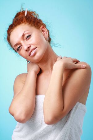 Smiling red haired woman in towel close up on a blue backgroundの写真素材