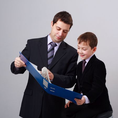 Business training. Father and son on a gray background.の写真素材