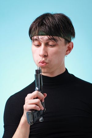 Young man with gun close up on a blue background.の写真素材