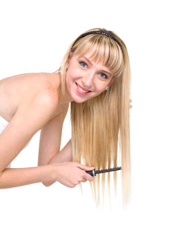 Young blonde woman combing her long hair, isolated on white backgroundの写真素材