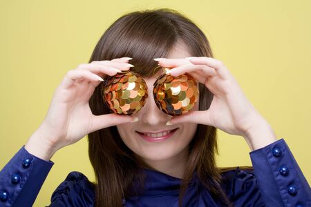 young smiling woman with Christmas decorations on a yellow backgroundの写真素材