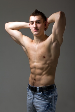 Beautiful and sexy muscular man posing on a gray backgroundの写真素材