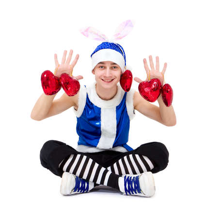 Christmas boy in blue santa hat with hearts sitting against isolated white backgroundの写真素材