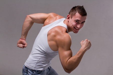 Smiling muscular man posing on a gray backgroundの写真素材