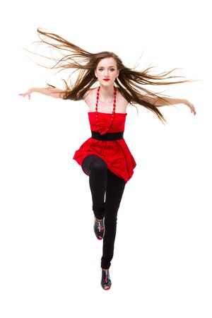 young woman with flying hair jumping on a white backgroundの写真素材