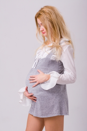 Portrait of adorable pregnant woman in modern dress on grayの写真素材