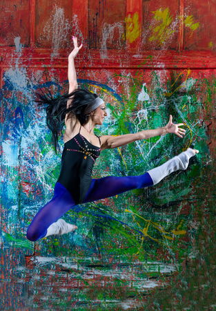 Portrait of a young lady, jumping in front of art graffitiの写真素材