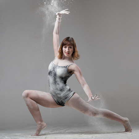 Beautiful expressive ballet dancer posing with flour at studio on grayの写真素材