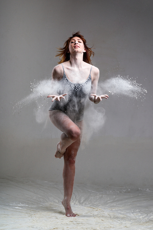 Beautiful expressive ballet dancer posing with flour at studio on grayの写真素材