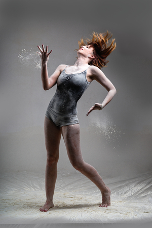 Beautiful expressive ballet dancer posing with flour at studio on grayの写真素材