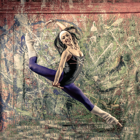 Portrait of fit young woman jumping in front of art wallの写真素材