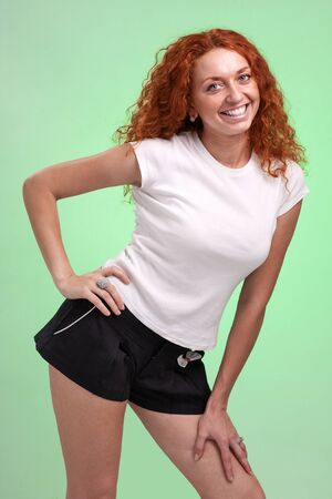 red-haired woman in little shorts, isolated on greenの写真素材