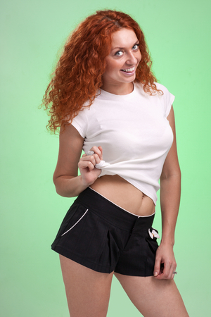 red-haired woman in little shorts, isolated on greenの写真素材