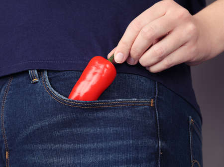Woman hand takes out Red chili pepper from pocket of her jeans.