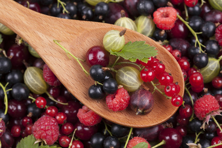 Berries in a wooden spoon on berries background. Close-up. 