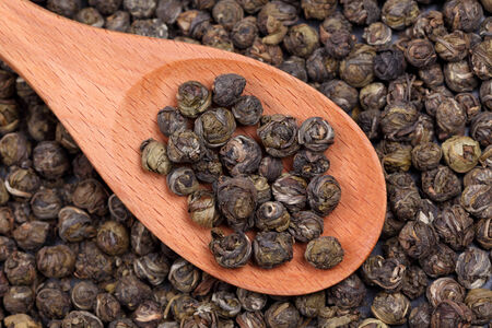 Organic green tea in a wooden spoon. Close-up.