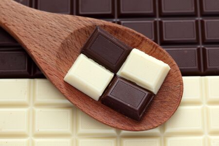 Dark and white chocolate in a wooden spoon. Close-up.