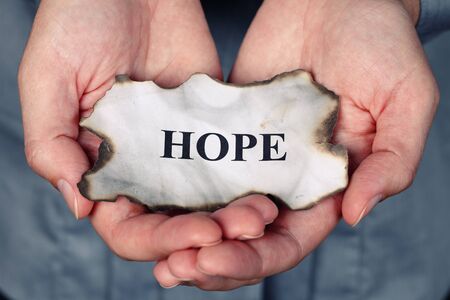 Burnt piece of paper with the word "Hope" in the woman's palms.の写真素材