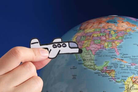 Airplane in a woman's hand flies against the globe