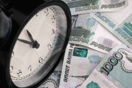 Time is money. Alarm clock and russian money.