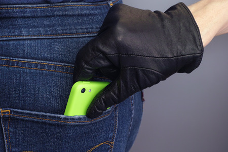 Thief stealing mobile phone from back pocket of a woman.の写真素材