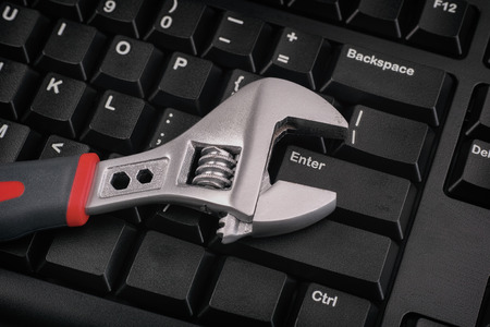 Computer repair concept. Wrench on a black keyboard.の写真素材