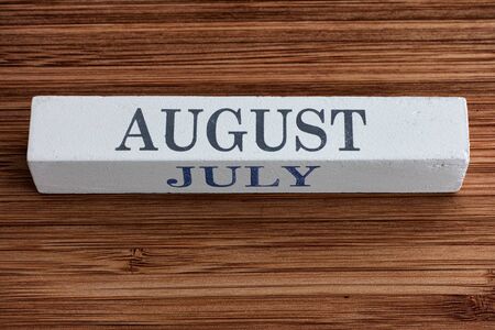 Wooden calendar with August and July months on a wooden background. Noise effect added.の写真素材