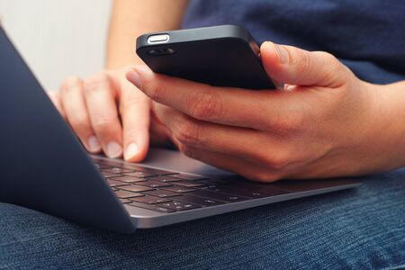 Young woman using a smartphone and laptop. Close up.の写真素材