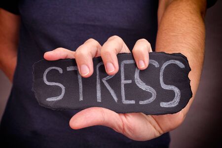 Woman holds Stress word written on black paper. Close up.