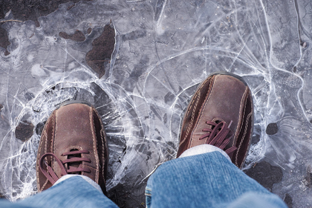 Man steps on frozen puddle with thin ice.の写真素材