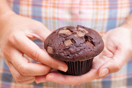 Woman holds Double chocolate chip muffin in her hands. Close up.の写真素材
