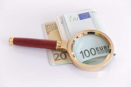 Magnifying glass and euro banknotes. Crisis concept.