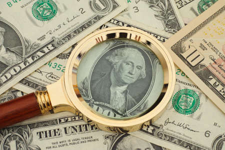 Magnifying glass and dollar bills. Crisis concept.