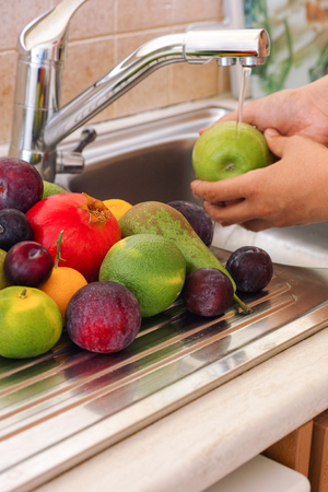 Person washing fruits in the sink.の写真素材
