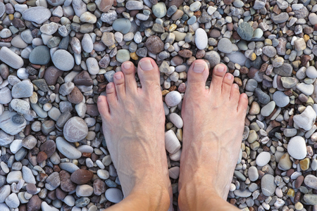 Feet on pebbles or stones. Relaxation and massage. Close up.の写真素材