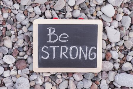 Phrase Be Strong on blackboard. Stone background. Close up.の写真素材