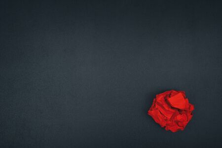 Red crumpled paper ball on a blackboard. Close up.の写真素材