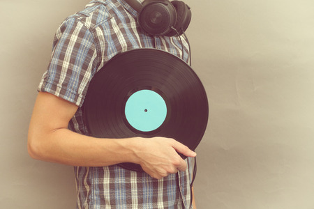 Man with headphones holds vinyl record in his hand.の写真素材