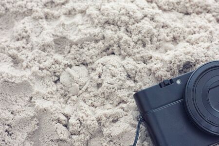 Black pocket camera laying on sand. Close up.の写真素材