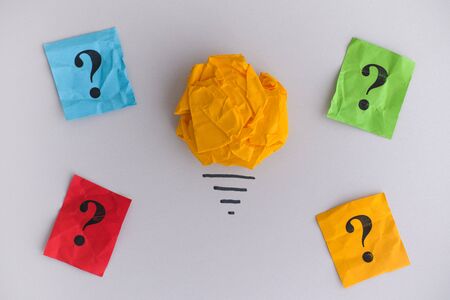 In Search of New Ideas or Innovations. Yellow crumpled paper ball as a light bulb and colorful question marks.の写真素材