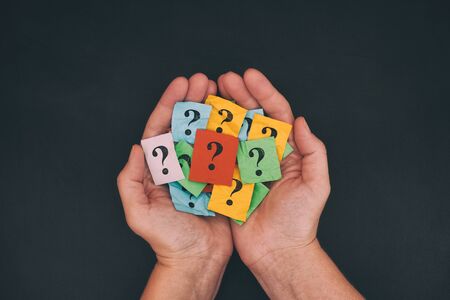 Too Many Questions. Pile of colorful paper notes with question marks in hands. Closeup.の写真素材