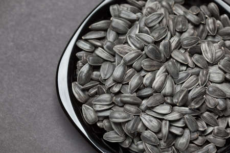 Sunflower seeds in a black plate. Black background.の写真素材