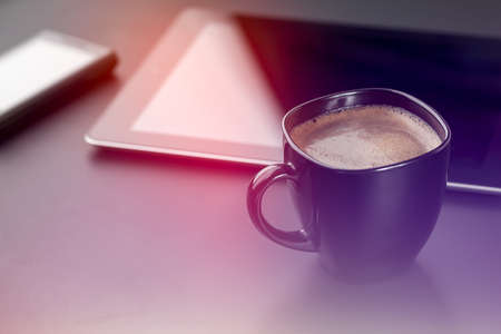 Cup of coffee, smartphone and digital tablet on a black desk.の写真素材