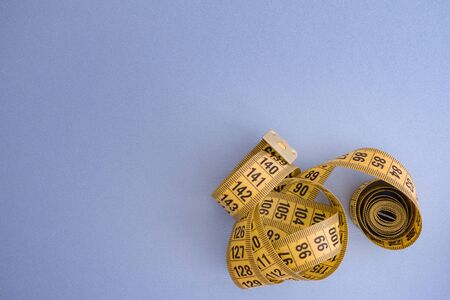 Yellow measuring tape on a blue background.