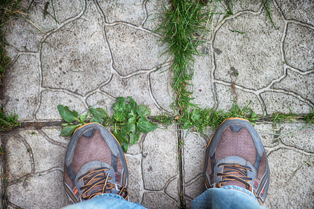 Feet in sneakers standing on the cobblestone tiles. Top view. Close up.の写真素材