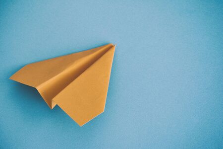 Yellow paper plane on a blue background. Close up.の写真素材