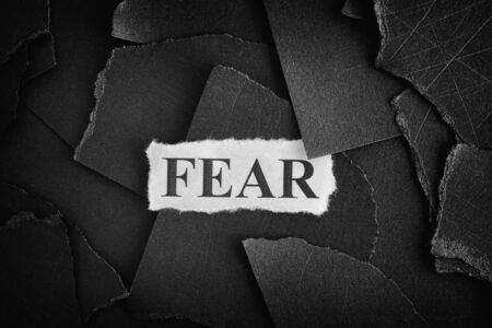 Fear. Torn pieces of black paper and word Fear. Concept Image. Black and White. Closeup.の写真素材